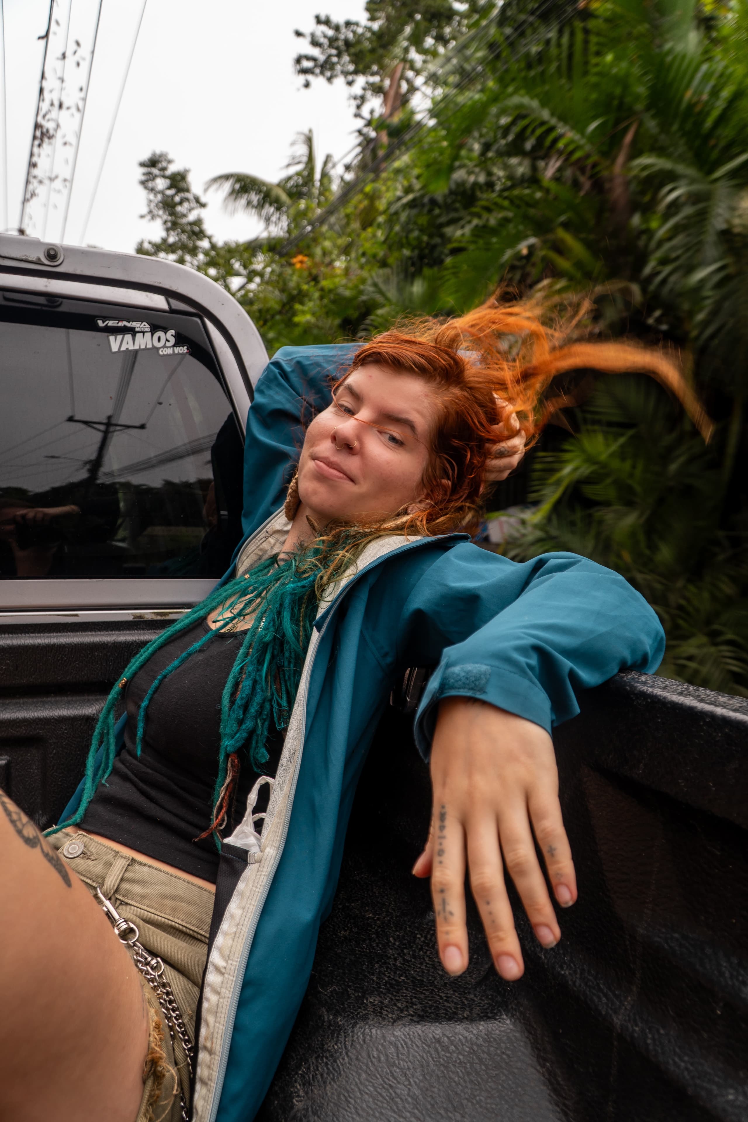 Agota reclining in the bed of a truck, wearing a teal jacket.